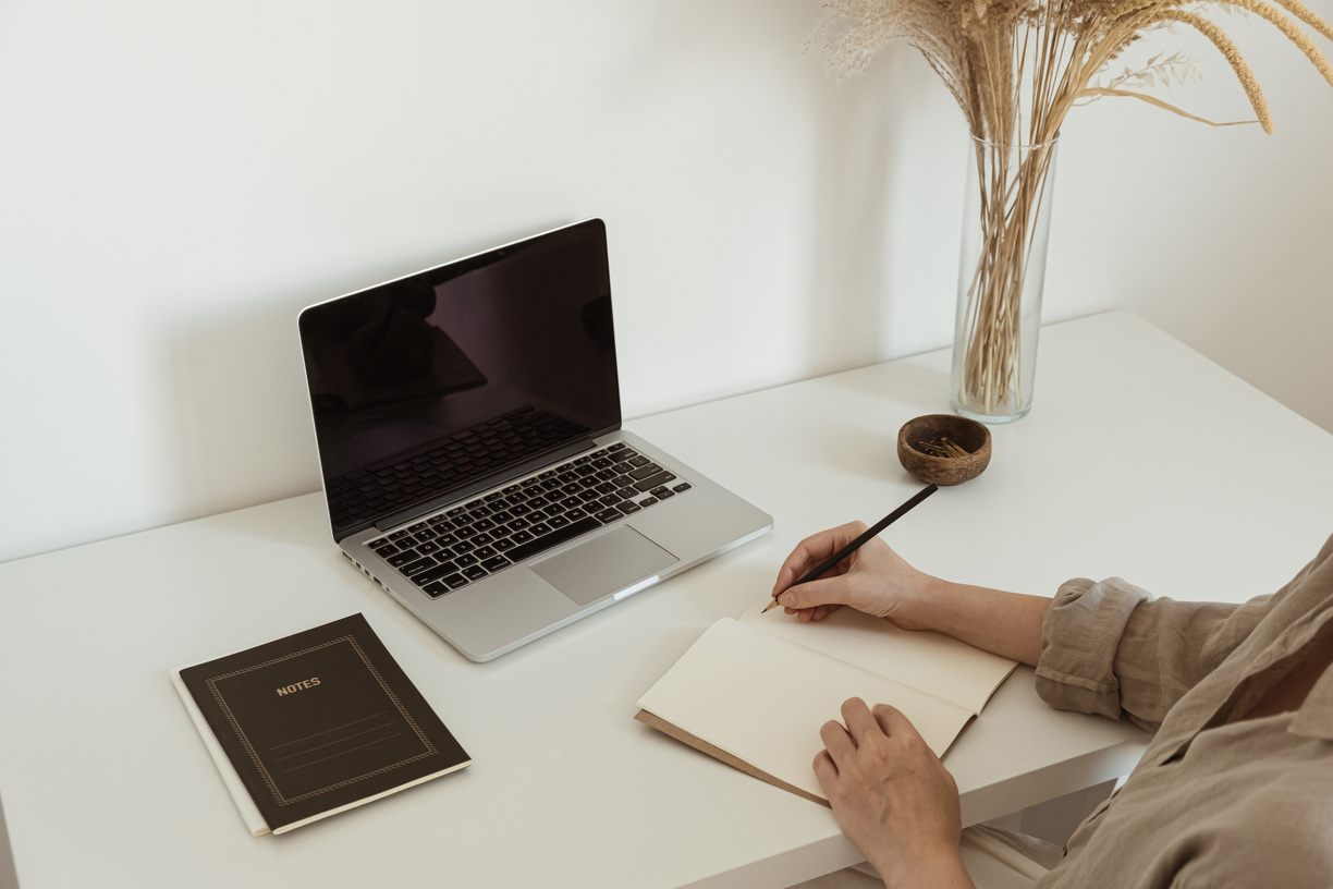 Woman Writing Notes in Notebook at her Desk 